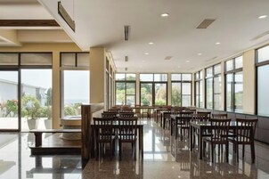 Un comedor amplio con una mesa larga y sillas, ventanas grandes y piso pulido.