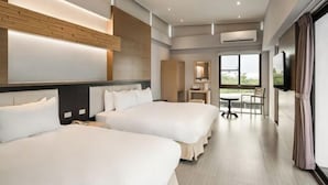 Een hotelkamer met twee bedden, een bureau, een stoel en een groot raam.