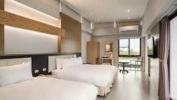 A hotel room with two beds, a desk, a chair, and a large window.