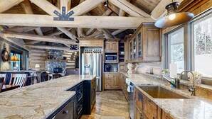 A spacious kitchen with granite countertops, wooden cabinets, and a large island. - Alpine Ridge on Whitefish Mountain Sleeps 12 (Whitefish)
