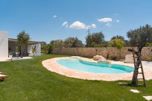 A swimming pool with a stone wall and a grassy area. - Villa Gia con Piscina Privata (San Michele Salentino)