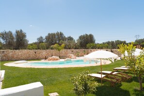 A backyard with a swimming pool, stone wall, and lounge chairs. - Villa Gia con Piscina Privata (San Michele Salentino)