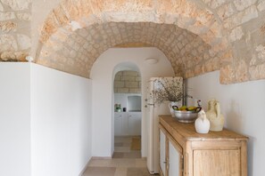 A kitchen with an arched stone ceiling, a wooden cabinet, and a bowl of fruit on the counter. - Villa Gia con Piscina Privata (San Michele Salentino)