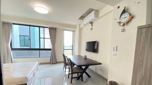 A hotel room with a bed, a dining table with chairs, a TV, a clock, and a window with curtains. - Chien Chien Backpacker Hostel Business Hotel Accommodation Nankexin City Shanhua Yongkang (Tainan)
