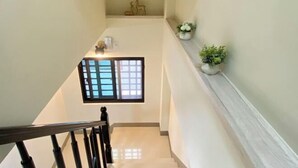 A staircase with a wooden handrail, a window with a grid pattern, and a small plant on the wall. - Chien Chien Backpacker Hostel Business Hotel Accommodation Nankexin City Shanhua Yongkang (Tainan)