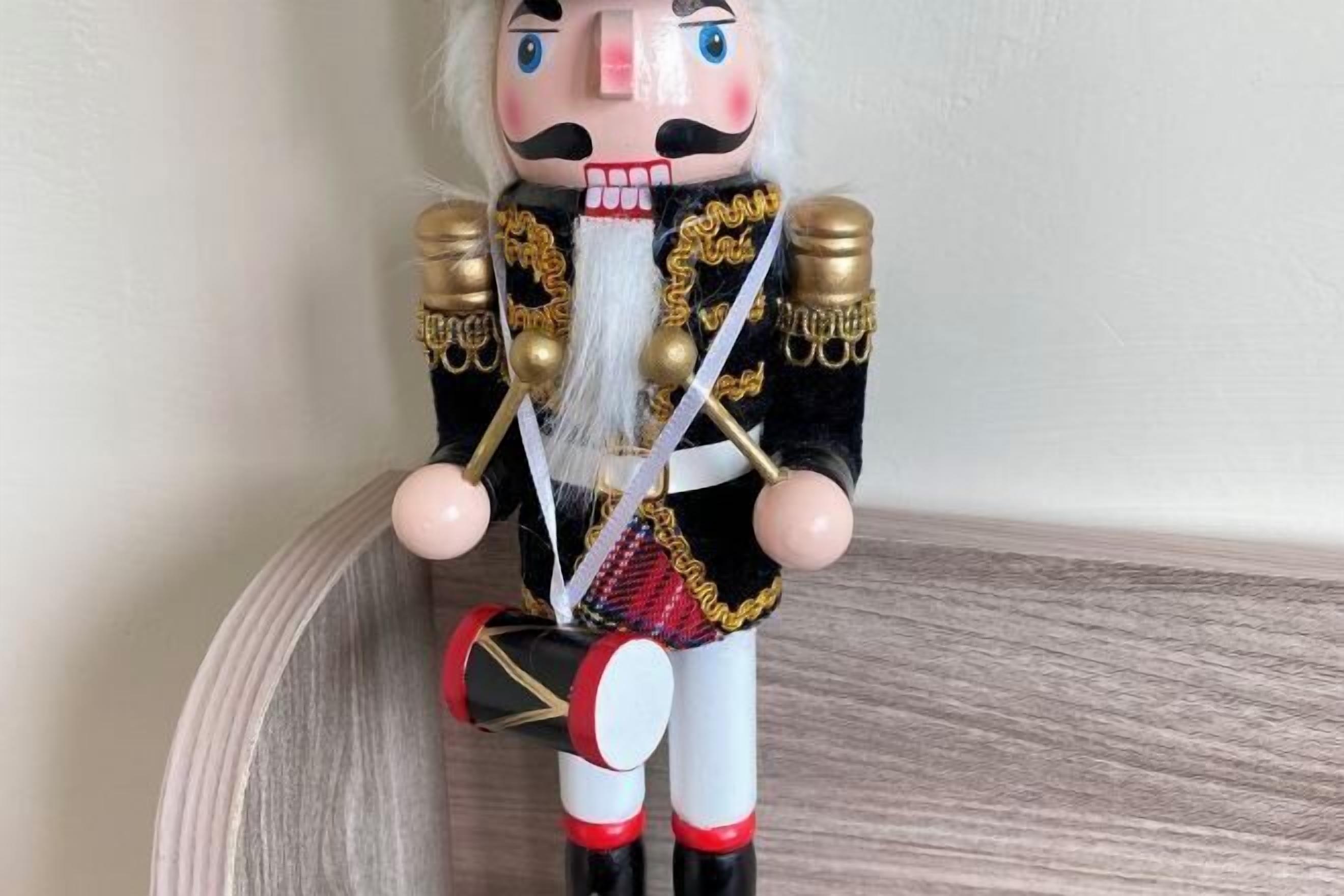 A nutcracker figurine with a white beard, black and gold outfit, and red and white boots.
