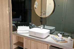 A modern bathroom with a white sink, a round mirror, and a wooden vanity. - Island Hearth Kaohsiung (Kaohsiung)