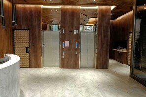 A reception area with a curved reception desk, wooden panel walls, and a marble floor. - Island Hearth Kaohsiung (Kaohsiung)