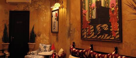 A cozy lounge area with a patterned sofa, a small round table, and a decorative chandelier.