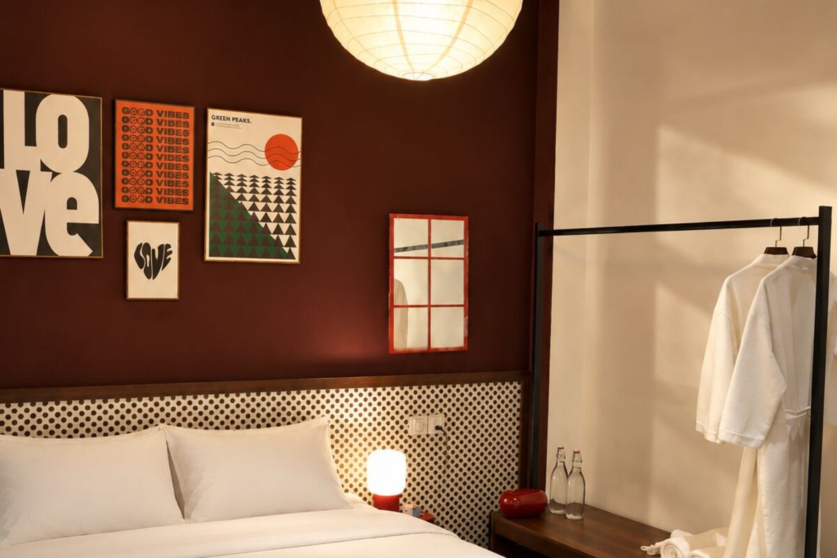 Una habitación de hotel con una cama grande, una lámpara colgante, una ventana con vistas y una obra de arte en la pared.