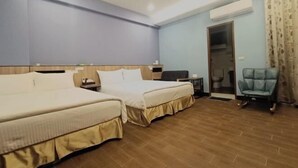 Habitación de hotel con dos camas, un escritorio, una silla y la puerta del baño.