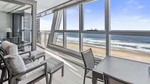 A balcony with a view of the ocean, furnished with chairs and a table. - Luxury Beachfront 1-Bed Apartment with Pool & Gym (Surfers Paradise)