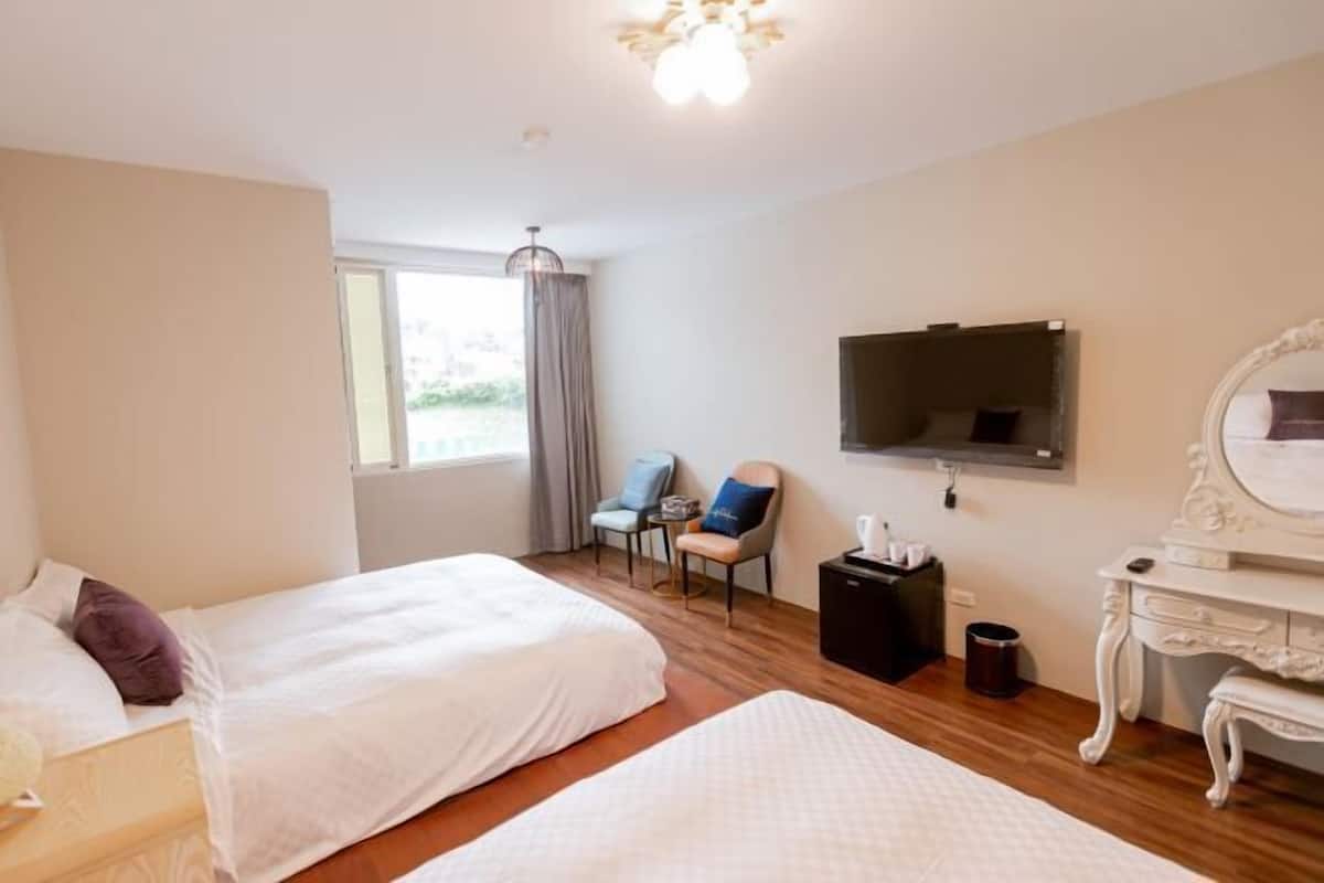 Una habitación de hotel con dos camas, televisión, escritorio y una silla.