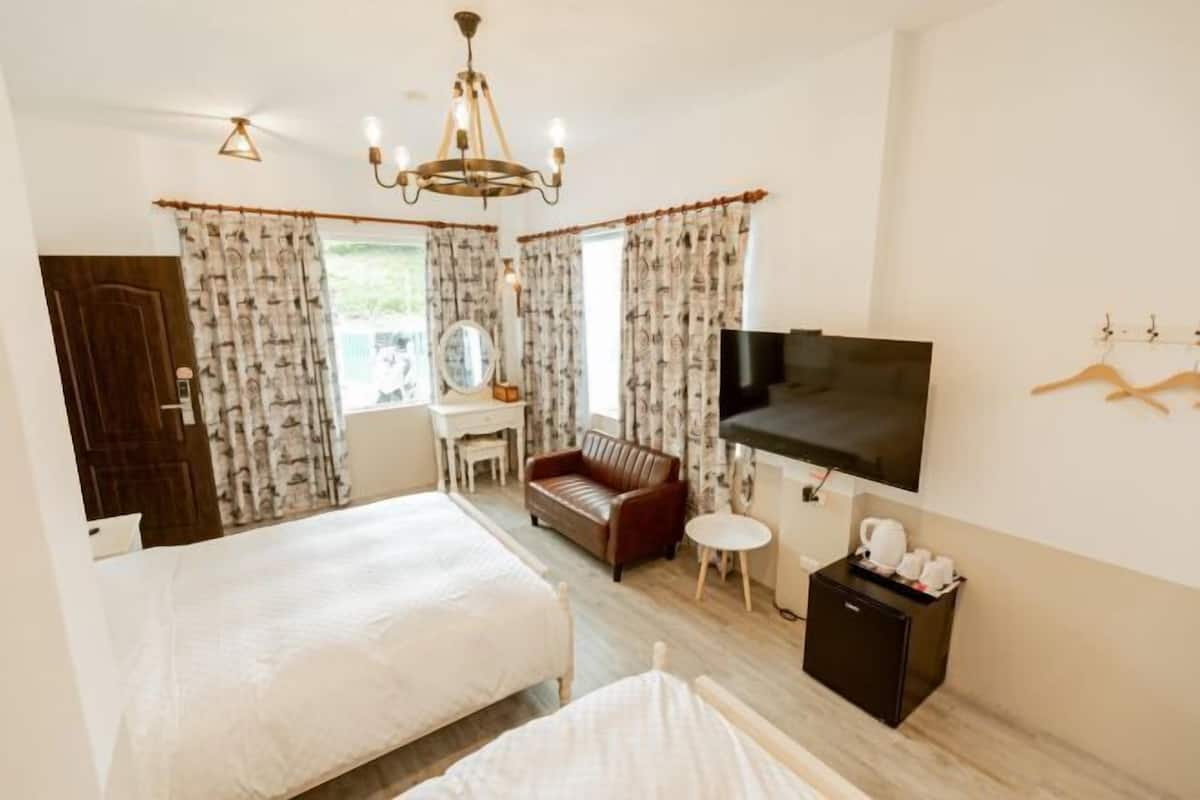 Una habitación de hotel con cama, sofá, televisión, escritorio y una mesita.