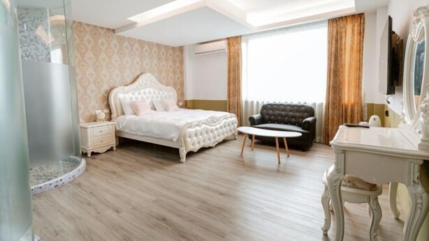 Een slaapkamer met een bed, een stoel, een bureau en een douchecabine van glas.
