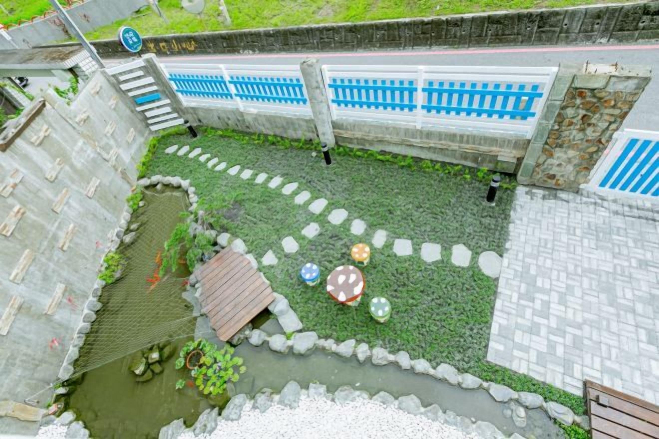 Un patio con un pequeño estanque, piedras para pisar y una estructura de madera.