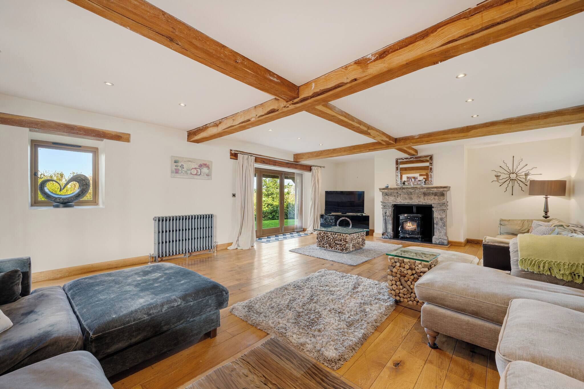 A spacious living room with wooden beams, a fireplace, a television, and comfortable seating.