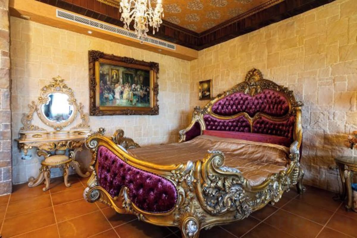 A bedroom with a large bed, ornate furniture, and a painting on the wall.