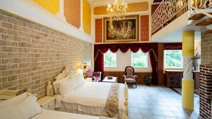 Ein Hotelzimmer mit einem großen Bett, einer Kandelaber, einem Gemälde und Blick ins Freie.