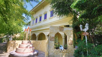 Um edifício com fachada de pedra, várias janelas e uma entrada central com um arco decorativo.