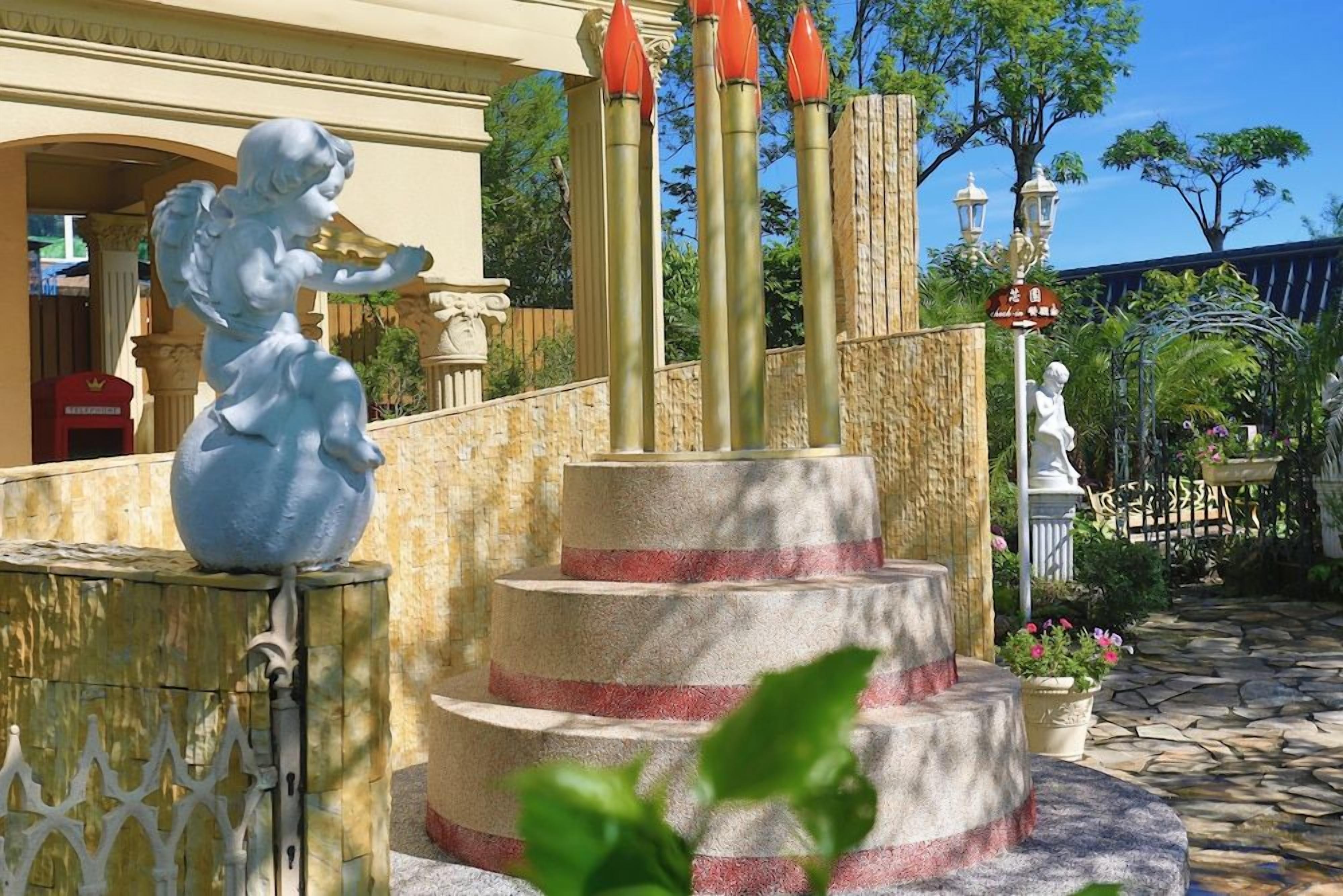 Una fontana con una statua di un angelo, una struttura a più livelli e un cartello con caratteri cinesi.