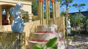 Una fontana con una statua di un angelo, una struttura a più livelli e un cartello con caratteri cinesi.