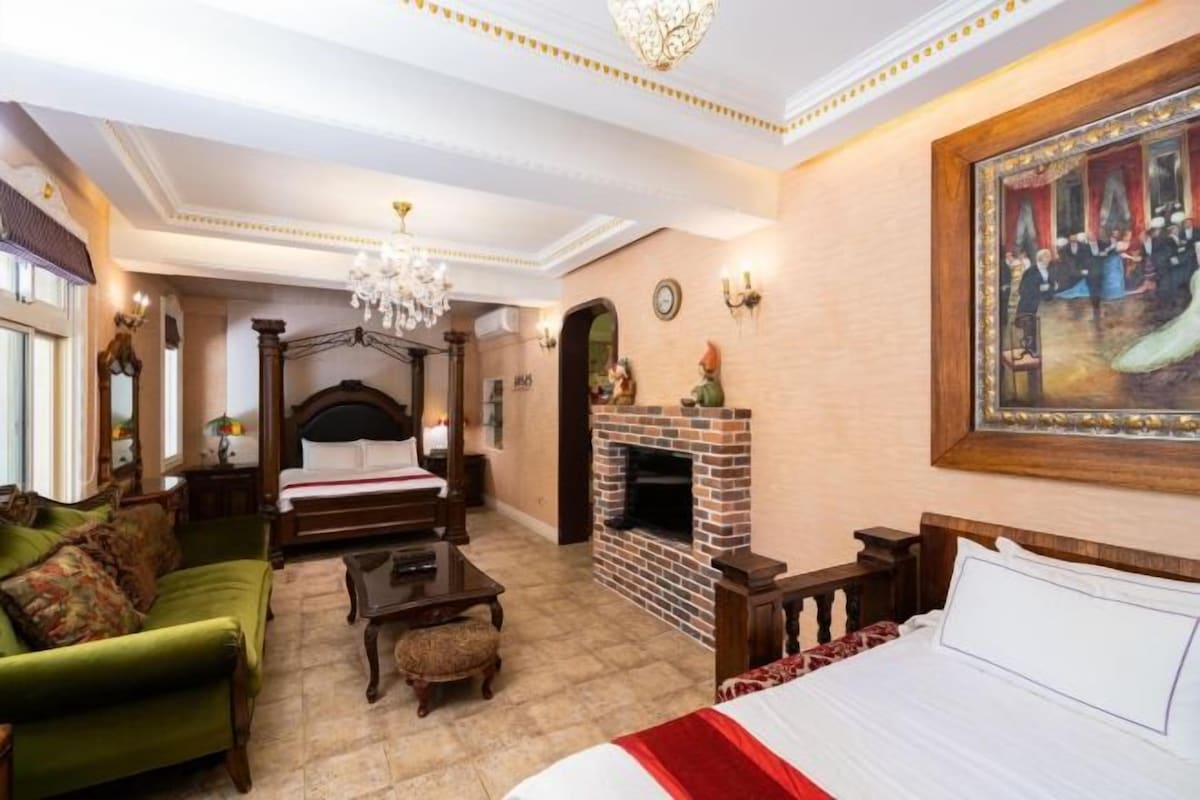 Une chambre à coucher avec un lit à baldaquin, une cheminée, un canapé vert et un grand tableau au mur.