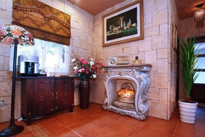 A room with a fireplace, a cabinet, a vase with flowers, and a painting on the wall. - Xinyuan My Dream Castle (Yilan)