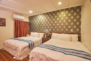 Une chambre d’hôtel avec deux lits, une table de chevet, une lampe et un papier peint à motifs.