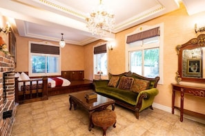 A room with a green sofa, a wooden coffee table, a fireplace, and a chandelier. - Xinyuan My Dream Castle (Yilan)