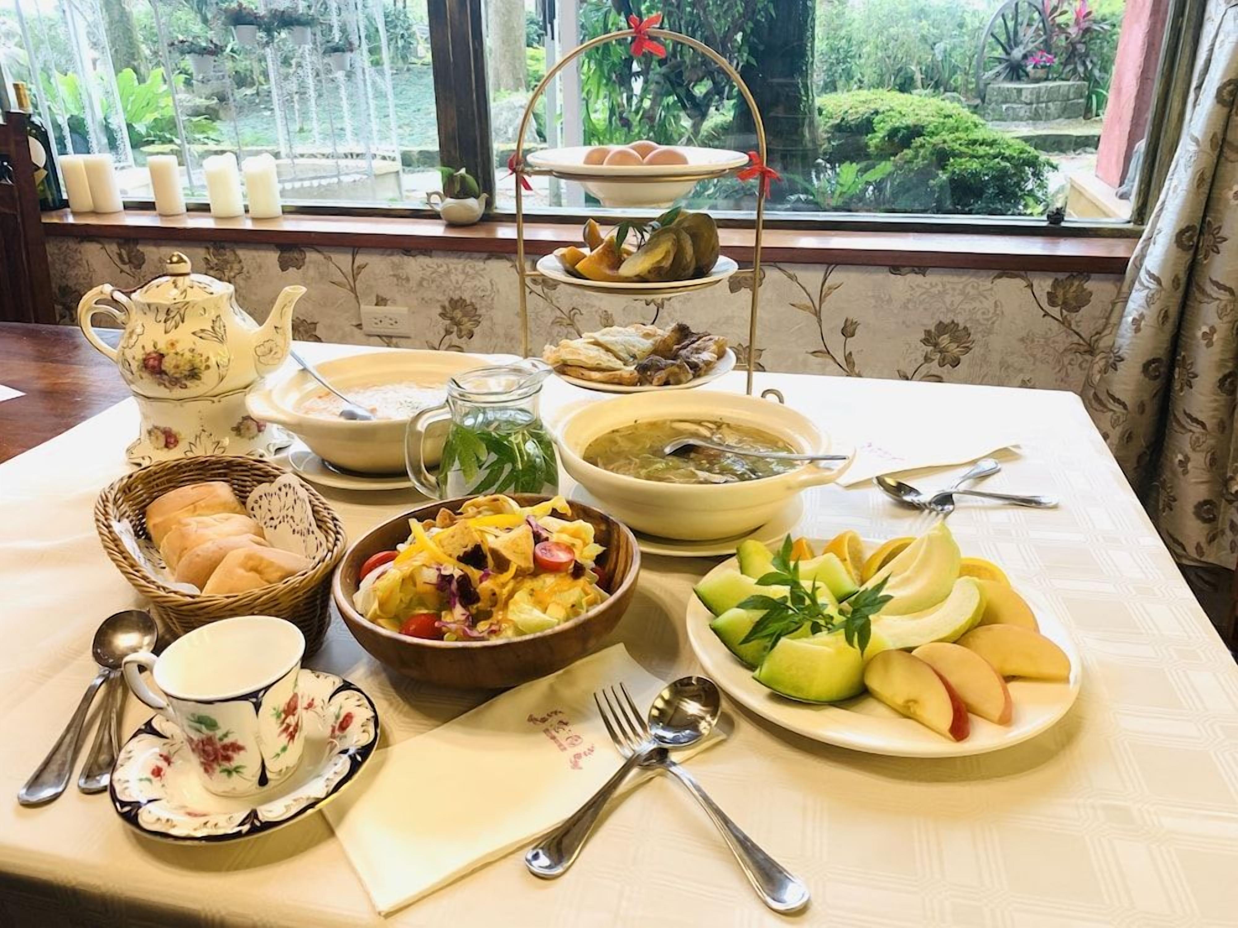 A table set with various dishes, a teapot, and a window view.