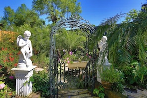 A garden with a metal archway, statues, and lush greenery. - Xinyuan My Dream Castle (Yilan)