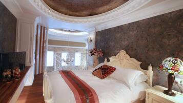 A bedroom with a large bed, a nightstand with a lamp, and a view of a brick wall.