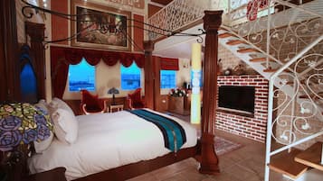 A four-poster bed with a canopy, a staircase with ornate railings, and a brick fireplace.
