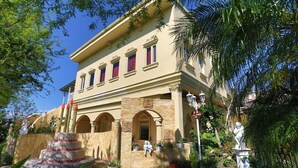 Ein Gebäude mit einer klassischen Fassade, Bogenfenstern und einer Steintreppe, die zum Eingang führt.