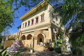 Un bâtiment à la façade classique, doté de fenêtres en arc de cercle et d’un escalier en pierre menant à l’entrée.