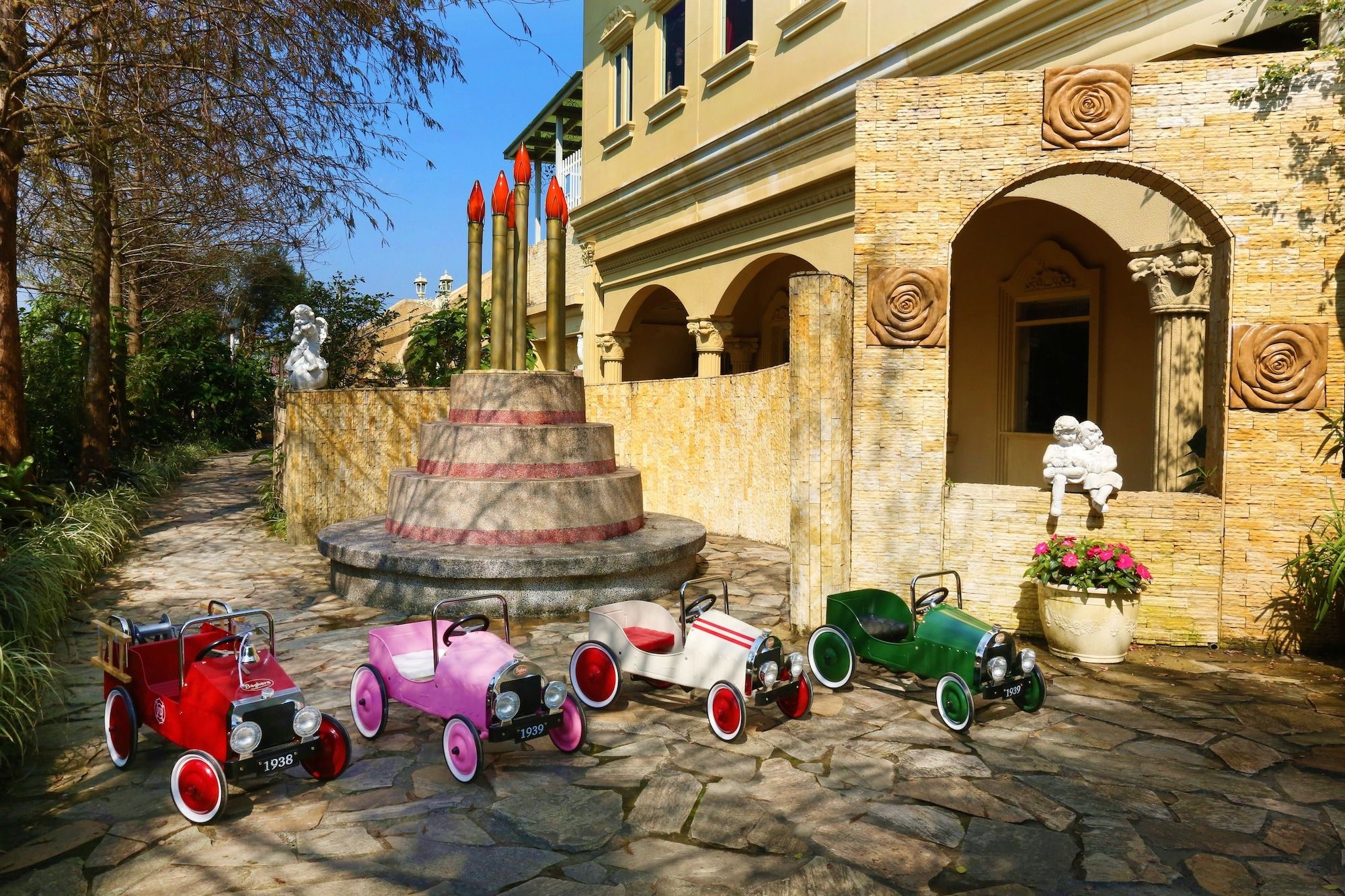 A courtyard with a fountain, stone steps, and vintage toy cars.