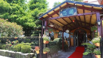 En traditionel japansk indgang med et rødt tæppe, der fører til en bygning.