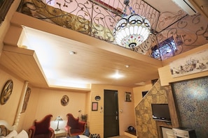 A room with a wooden ceiling, a chandelier, a television, and a stone wall. - Xinyuan My Dream Castle (Yilan)