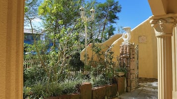Un corredor exterior con suelo de baldosas, pared de piedra y un farol.