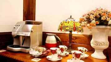A coffee machine, teapot, teacups, teapot, and a vase with flowers on a wooden table.