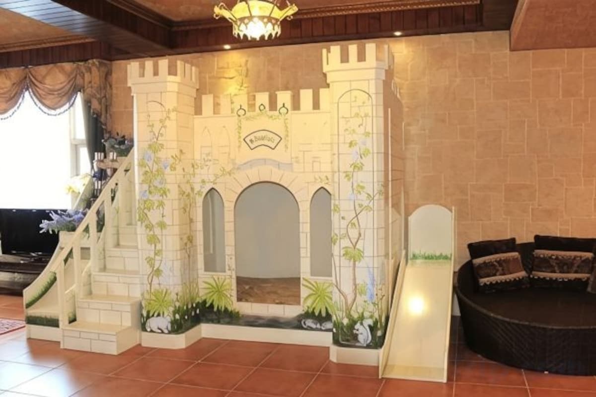 A castle-themed play area with a slide, archways, and a seating area.