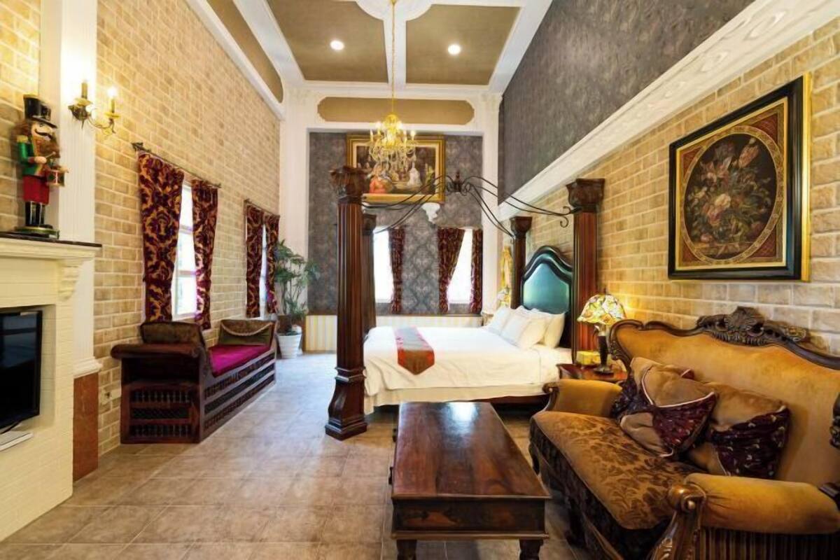 Een kamer met een bed, een bank, een open haard en een kroonluchter.