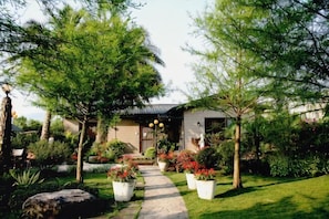 A pathway leading to a house surrounded by lush greenery and potted plants. - Xin Yuan-My Dream Castle (Yilan)