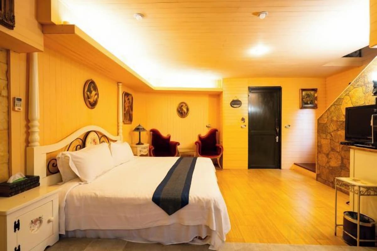 Een hotelkamer met een bed, bureau, stoel, televisie en een trap.