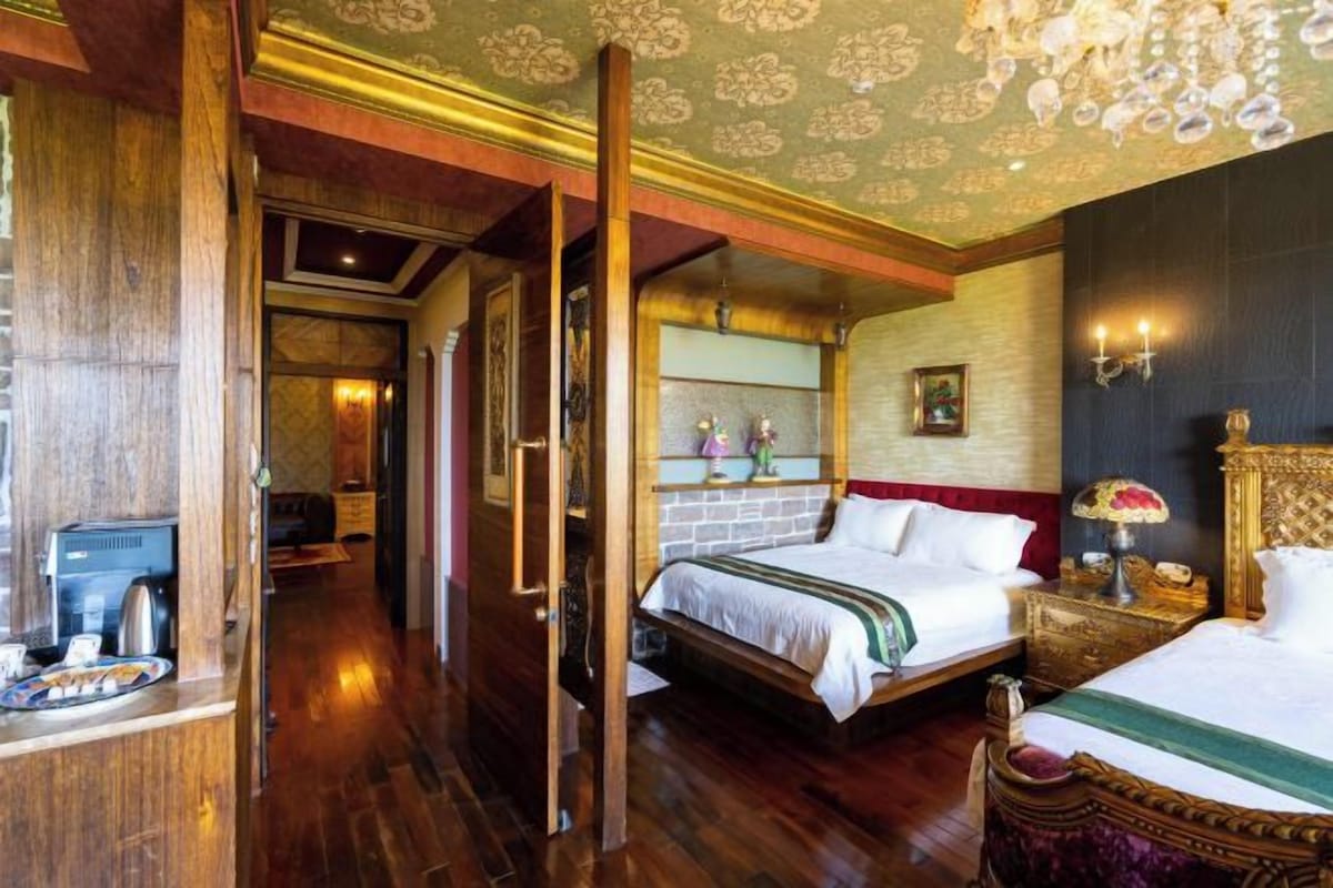 Une chambre d’hôtel avec un plancher en bois, un lit avec une literie blanche, une table de chevet avec une lampe et un lustre.