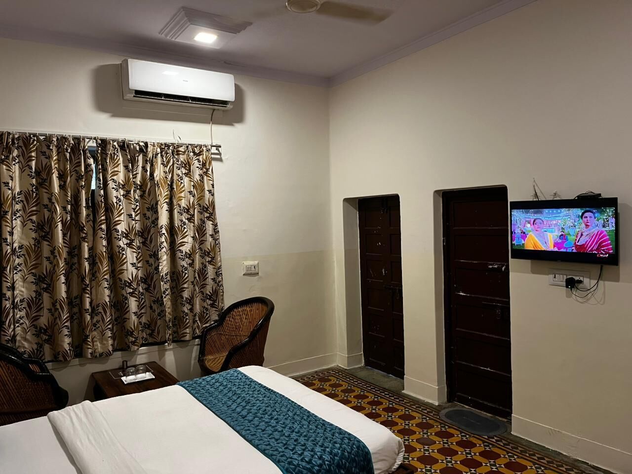 Una habitación de hotel con una cama, televisión, aire acondicionado y una puerta.