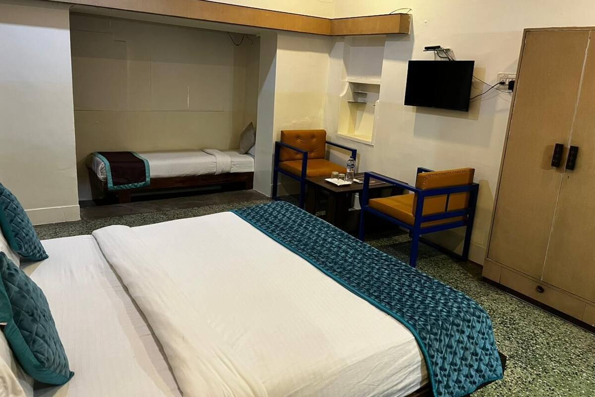 Een hotelkamer met een bed, een tafeltje, twee stoelen, een televisie en een kledingkast.