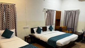 Ein Hotelzimmer mit zwei Betten, einem Holzschrank, einem kleinen Tisch und einem Stuhl.