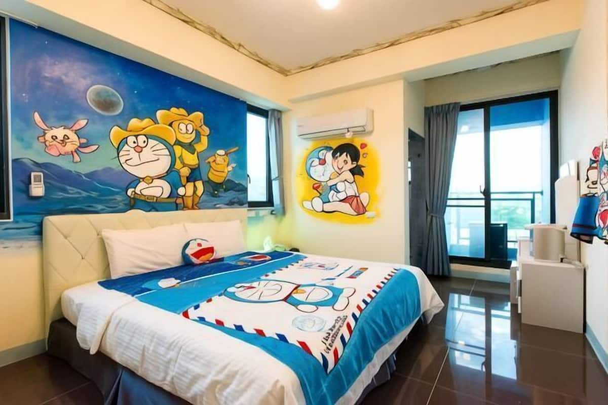 A hotel room with a large bed, a mural with cartoon characters, a window with a view, and a balcony.